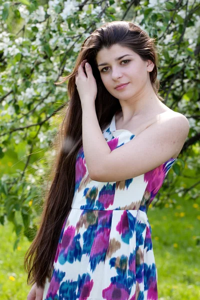 A menina de cabelos longos contra macieiras florescentes . — Fotografia de Stock