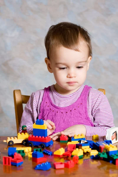 Dítě v růžových šatech s hračkami — Stock fotografie