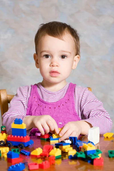 Dítě v růžových šatech s hračkami — Stock fotografie