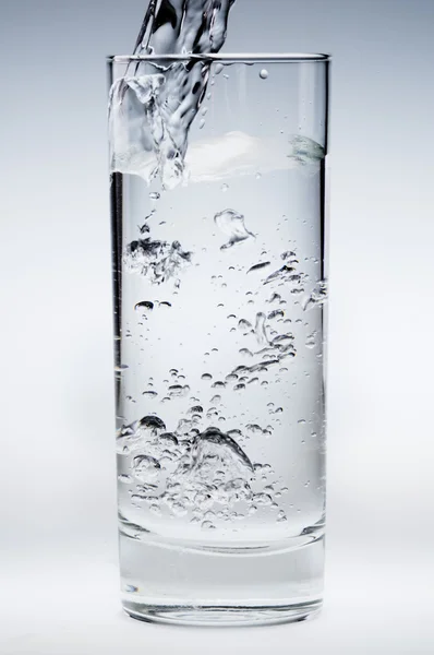 Hälla vatten ström i ett glas — Stockfoto