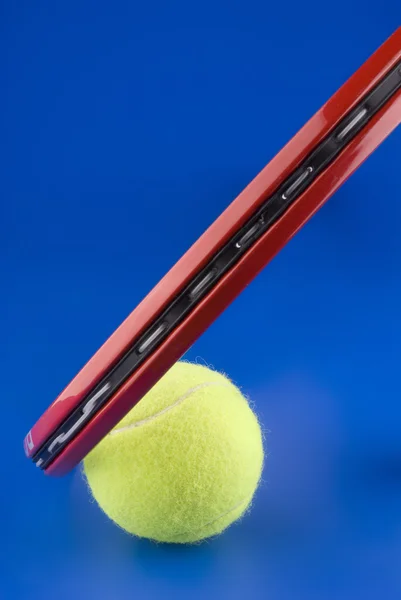 テニス ・ ボール、テニス ラケット、青い背景に隠れて上の部分の横にあります。 — ストック写真