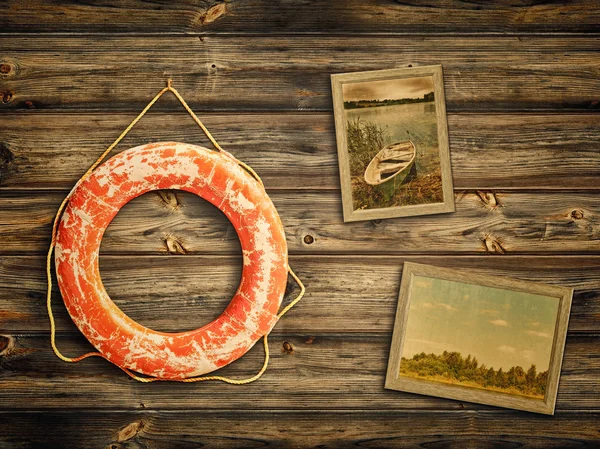 Lifebuoy and old travel photos at wooden background — Stock Photo, Image