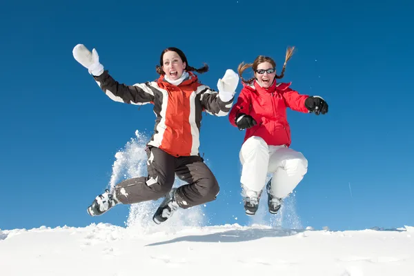 Meisjes zitten en lachend in sneeuw op zonnige dag - Winterpret — Stockfoto