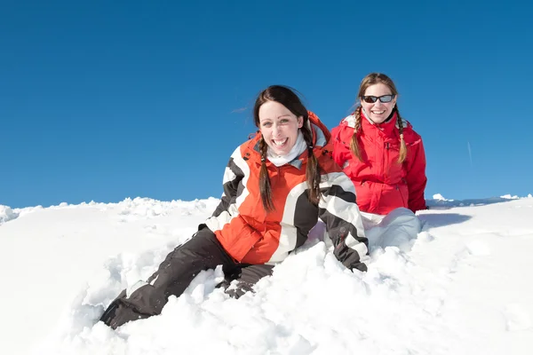 Chicas sentadas y sonriendo en la nieve en el día soleado - diversión de invierno —  Fotos de Stock