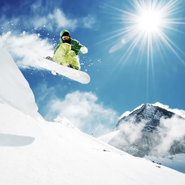 Snowboarder en salto enaltas montañas Imagen De Stock