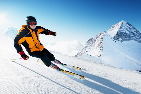 Лыжник в горах, подготовленные трассы и солнечный день
