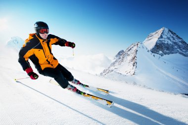 Skier in mountains, prepared piste and sunny day clipart