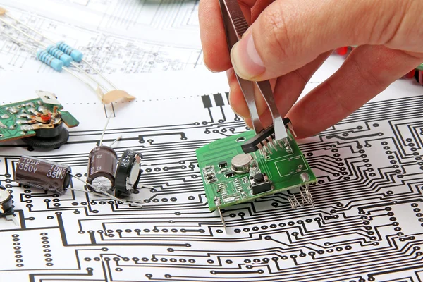A hand hand with tweezers holding a electronic circuit board on — Stock Photo, Image
