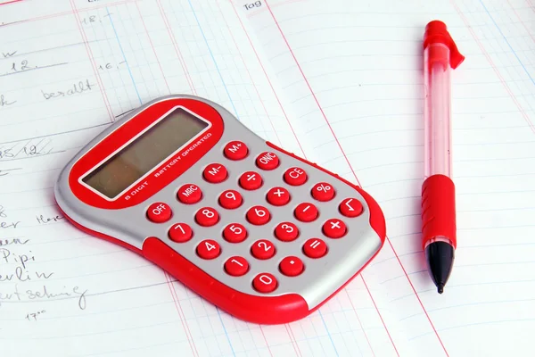 Red calculator on a notebook and red pencil — Stockfoto