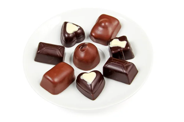Assorted chocolates on a white saucer — Stok fotoğraf