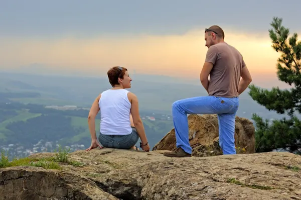 Mann und Frau auf dem Gipfel des Berges bei Sonnenuntergang Stockbild