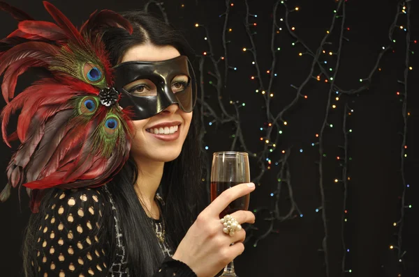 Lady in fancy mask with a glass of wine on black background