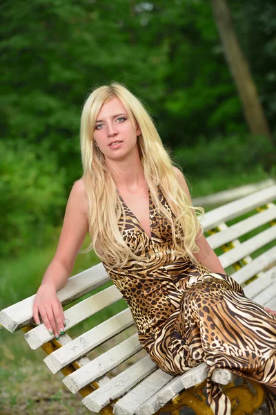 Porträtt av en vacker kvinna i en park på en bänk — Stockfoto