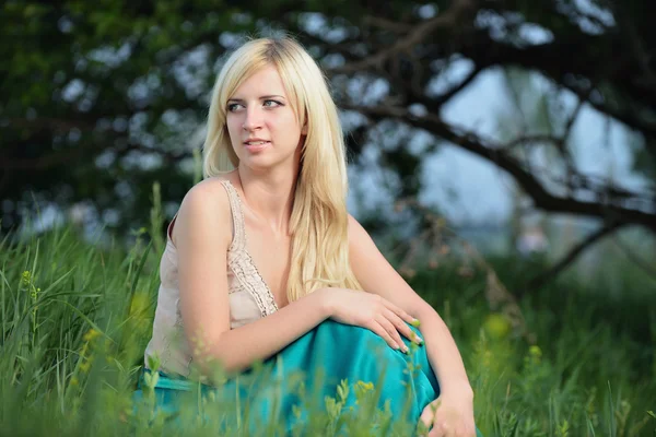 Porträtt av en vacker kvinna som sitter i gräset — Stockfoto