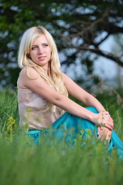 Portret van een mooie vrouw zitten in het gras — Stockfoto