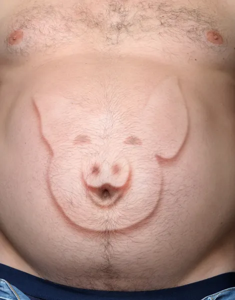 Человеческий живот от свинки, торчащей из-за изображения — стоковое фото