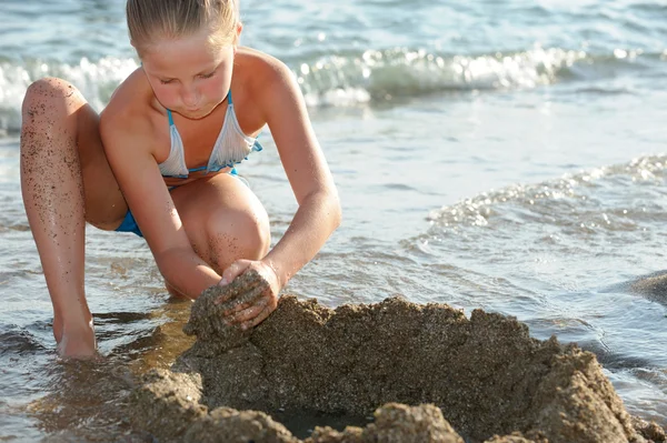 Девушка строит замок из песка — стоковое фото
