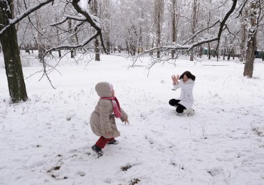 Mum and the daughter play snowballs clipart