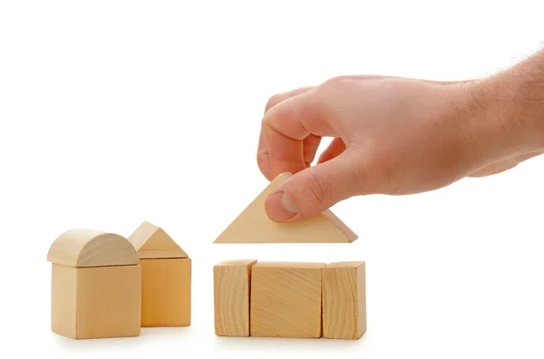 De hand stelt een speelgoed dak op houten kubussen — Stockfoto