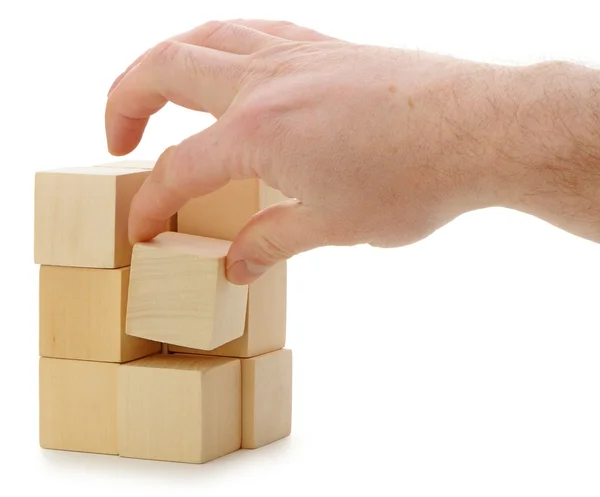 De hand stelt een houten kubus — Stockfoto