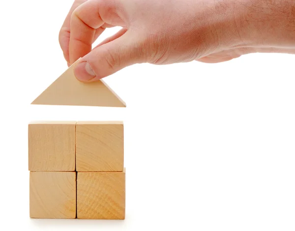 The hand establishes a toy roof on wooden cubes — Stock Photo, Image