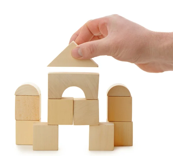 De hand stelt een speelgoed dak op houten kubussen — Stockfoto