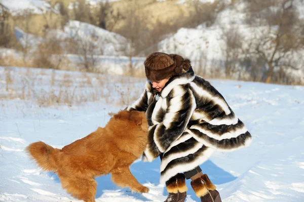 Η γυναίκα σε ένα γούνινο παλτό βιζόν που παίζει με ένα σκυλί — Φωτογραφία Αρχείου