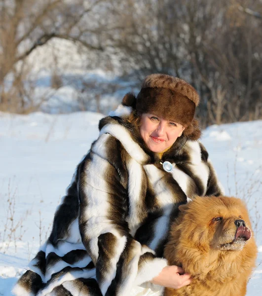 A mulher em um casaco de peles de marta joga com um cão — Fotografia de Stock