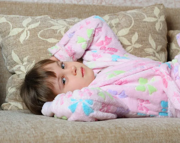 Маленькая девочка лежит на диване — стоковое фото