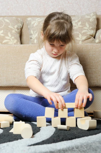 A menina joga cubos de brinquedo de madeira — Fotografia de Stock