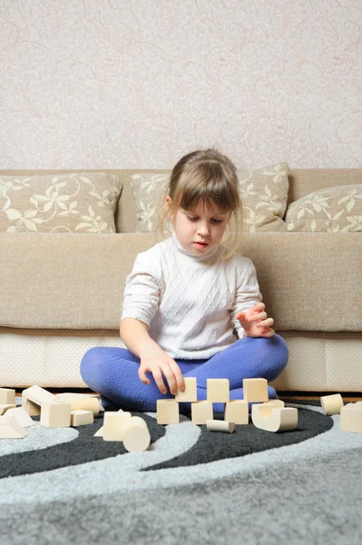 A menina joga cubos de brinquedo de madeira — Fotografia de Stock