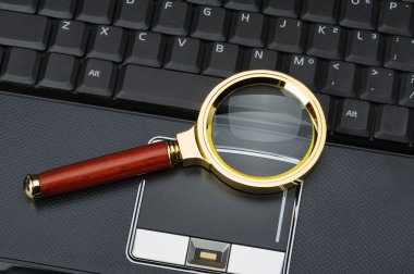 Magnifying glass and a laptop clipart