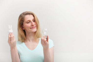 Woman choosing a light bulb clipart