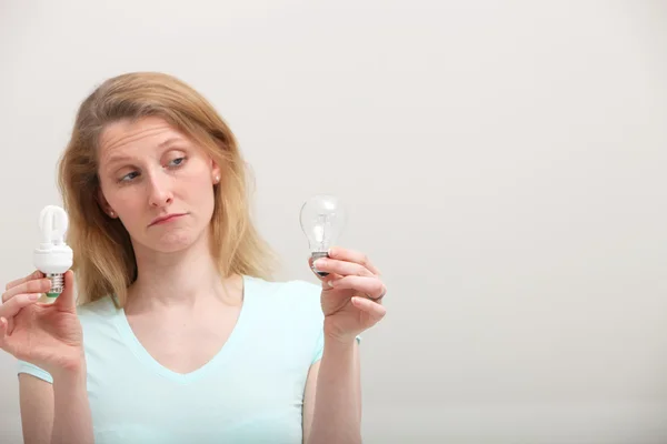 Woman eyeing incandescent light bulb — Stock Photo, Image