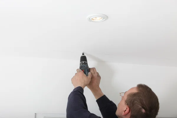 Man Drilling White Ceiling Stock Image