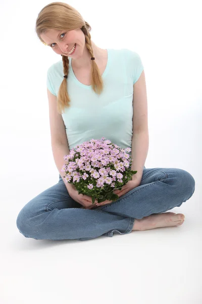Attractive woman sitting and holding flowers — Stock Photo, Image