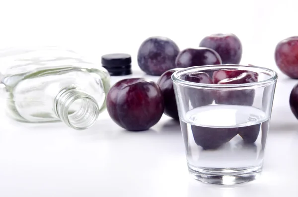 Acquavite di prugne in un bicchiere e prugne fresche — Foto Stock