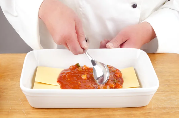 Köchin mit Tomatensauce und einem Löffel — Stockfoto