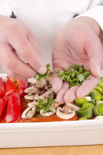 Chef spread fresh herbs on lasagna — Stock Photo, Image