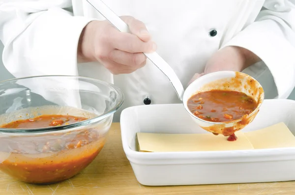 Vrouwelijke chef-kok met tomatensaus in een pollepel — Stockfoto