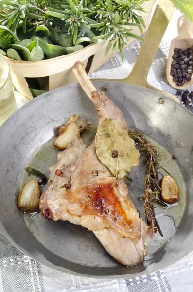 Rabbit leg with herbs in a brass pan — Stock Photo, Image