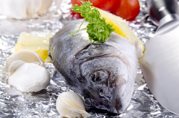 Sea ​​bass on an aluminum foil with vegetables — Stock Photo, Image