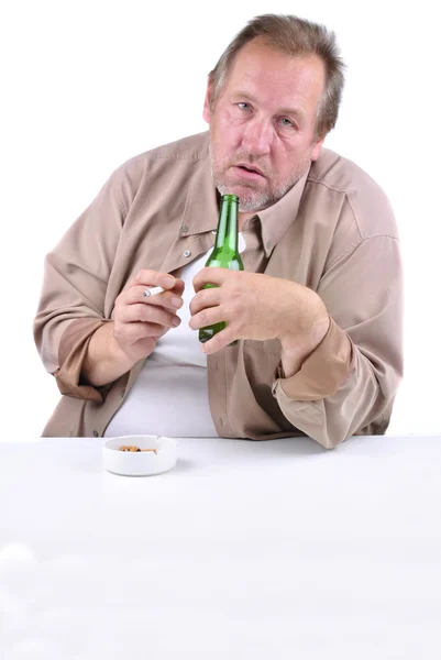 Ужасный мужчина лет 50, сидит за столом с пивом — стоковое фото