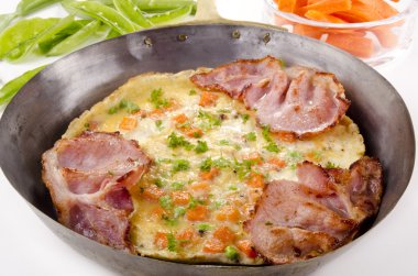 Omelette with carrot and bacon in a pan clipart