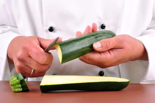 Chef donna tagliare una zucchina con un coltello da cucina — Foto Stock