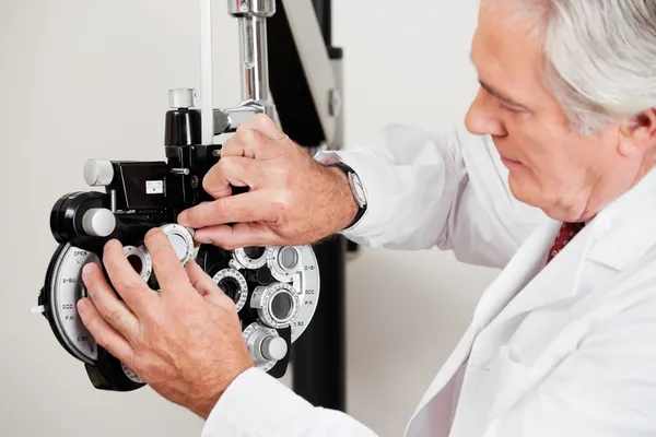 Оптометрист, устанавливающий фороптер для испытания на зрение — стоковое фото