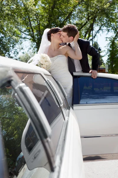 Pareja recién casada de pie junto a la limusina —  Fotos de Stock