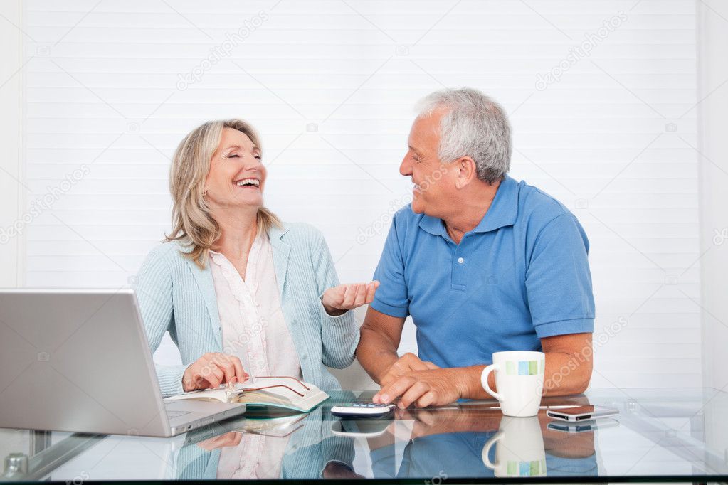 Couple At Dining Table Working on Laptop