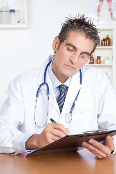 Doctor masculino escribiendo en portapapeles — Foto de Stock