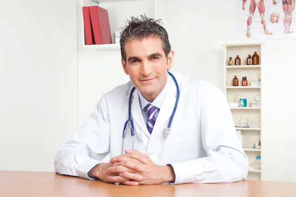 Мужской врач сидит за столом — стоковое фото